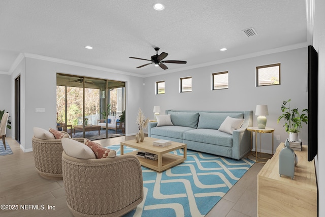 living room featuring ceiling fan, a textured ceiling, and crown molding