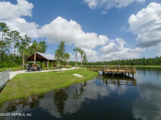 view of dock with a water view and a lawn