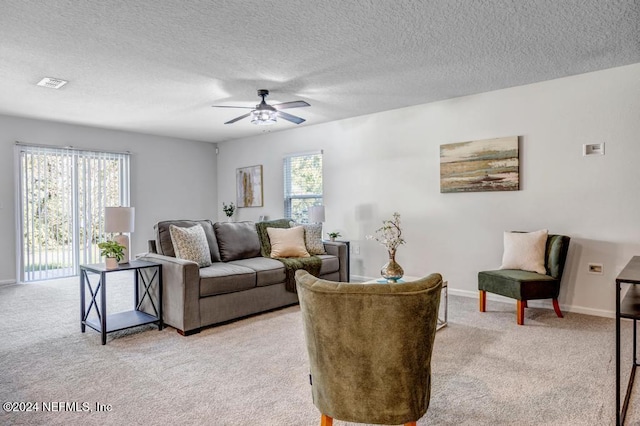 living room featuring a textured ceiling, light colored carpet, plenty of natural light, and ceiling fan