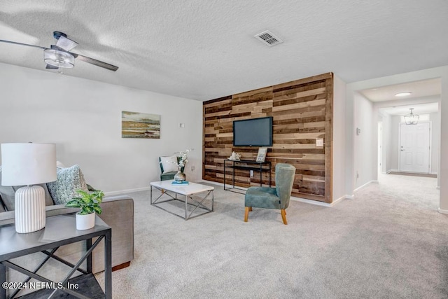 living room featuring a textured ceiling, ceiling fan, light colored carpet, and wooden walls