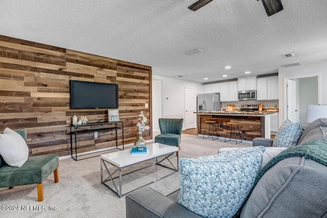 carpeted living room featuring wood walls and a textured ceiling