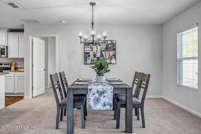 dining space with light carpet and an inviting chandelier