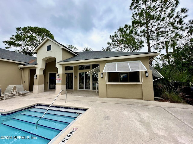 rear view of property featuring a community pool and a patio