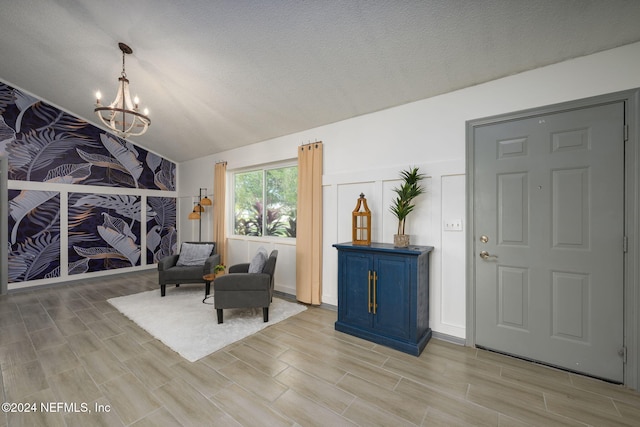 living area featuring a textured ceiling, light hardwood / wood-style flooring, lofted ceiling, and an inviting chandelier