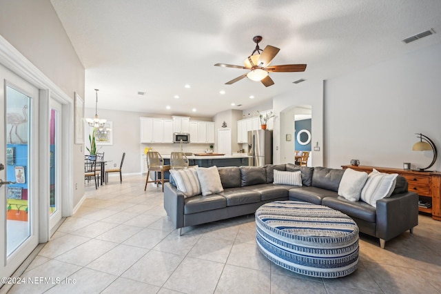 tiled living room with a textured ceiling and ceiling fan with notable chandelier