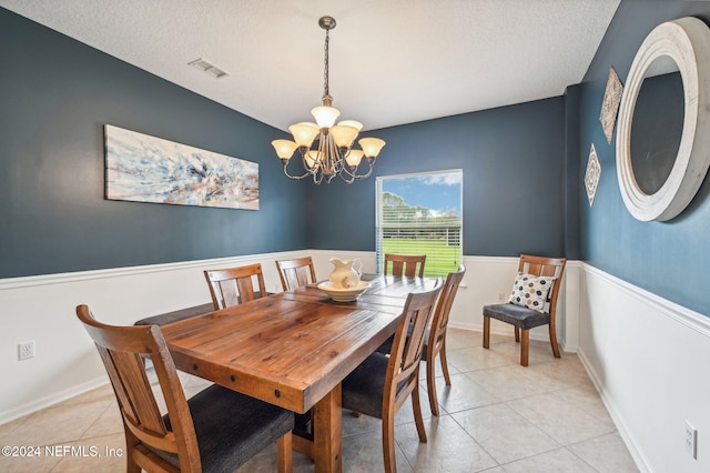 dining room featuring a textured ceiling, an inviting chandelier, and light tile patterned floors