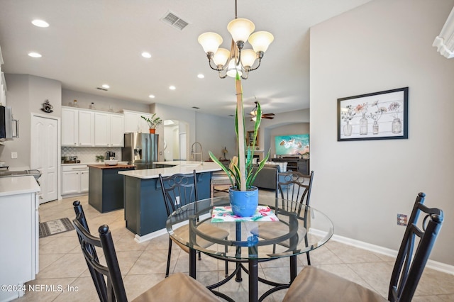 tiled dining area with sink and ceiling fan with notable chandelier