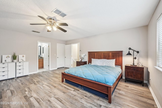 bedroom with ensuite bathroom, light hardwood / wood-style floors, and ceiling fan