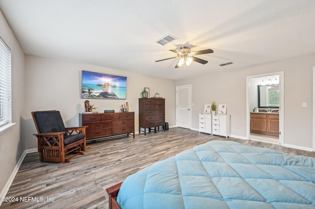 bedroom with ensuite bathroom, light wood-type flooring, and ceiling fan