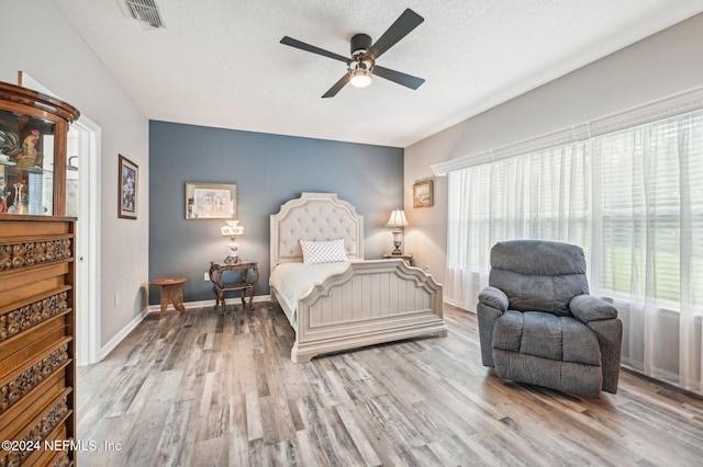 bedroom featuring ceiling fan, a textured ceiling, and light wood-type flooring