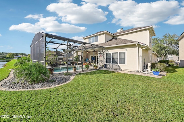 rear view of house with ceiling fan, a patio area, glass enclosure, and a lawn