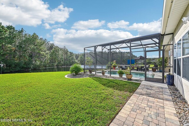 view of yard featuring a patio area, a water view, and glass enclosure