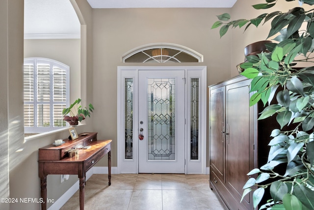 foyer entrance featuring crown molding and light tile patterned floors