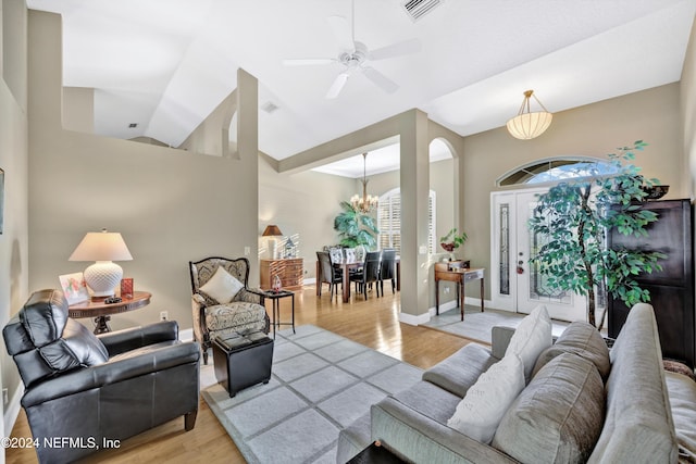 living room featuring high vaulted ceiling, ceiling fan with notable chandelier, and light wood-type flooring