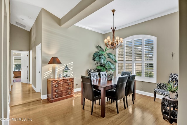 dining area with a notable chandelier, ornamental molding, and light wood-type flooring