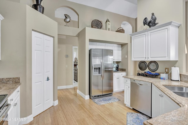 kitchen featuring light stone counters, appliances with stainless steel finishes, light wood-type flooring, and white cabinets