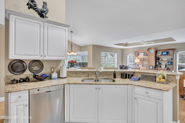 kitchen with kitchen peninsula, a tray ceiling, dishwasher, light hardwood / wood-style floors, and sink