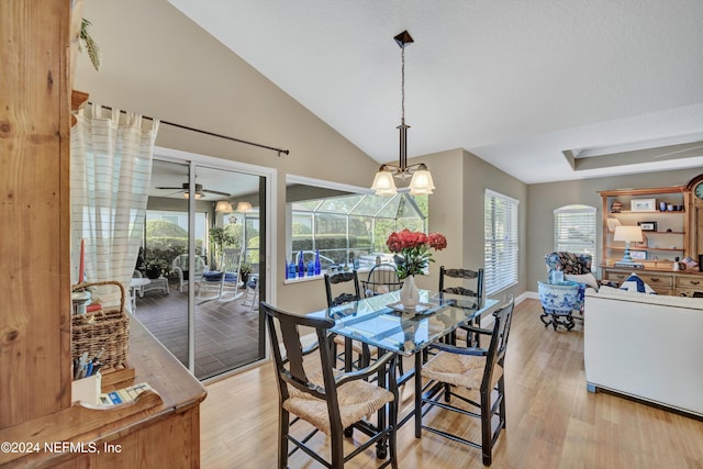 dining area featuring light hardwood / wood-style floors, ceiling fan with notable chandelier, and vaulted ceiling