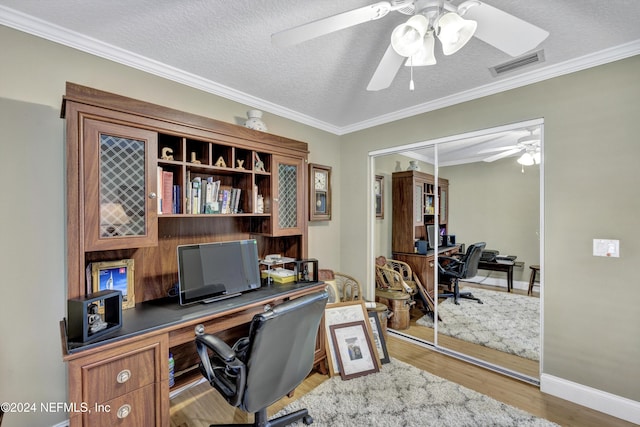 office space featuring built in desk, a textured ceiling, ceiling fan, hardwood / wood-style flooring, and ornamental molding