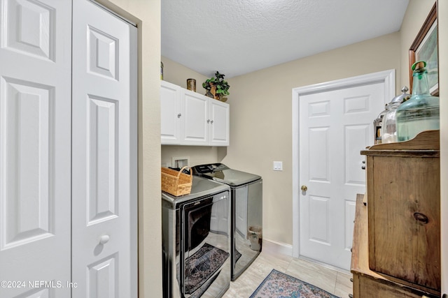 kitchen with a textured ceiling, white cabinets, washing machine and clothes dryer, and light tile patterned flooring