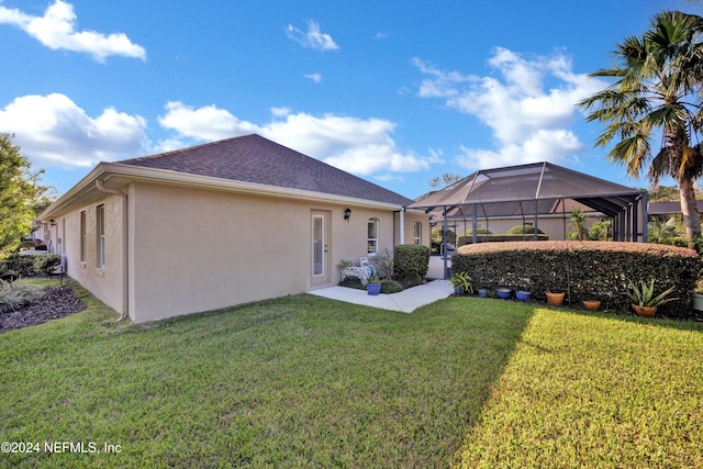 rear view of property with a patio, a lawn, and a lanai