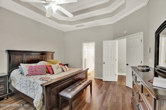 bedroom with a high ceiling, a tray ceiling, crown molding, dark hardwood / wood-style flooring, and ceiling fan