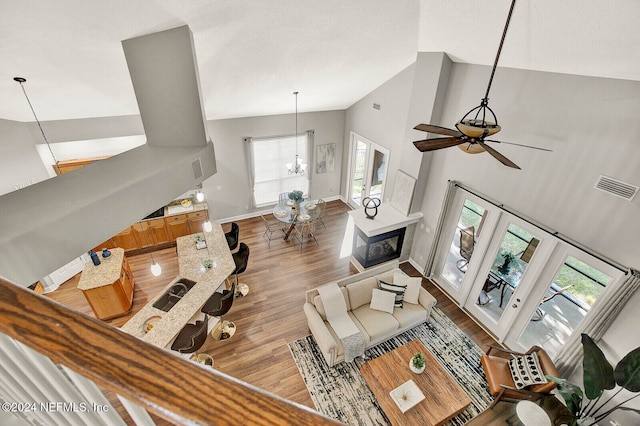 living room with high vaulted ceiling, light wood-type flooring, and ceiling fan with notable chandelier