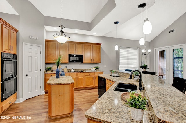 kitchen featuring a center island with sink, sink, decorative light fixtures, and light hardwood / wood-style floors