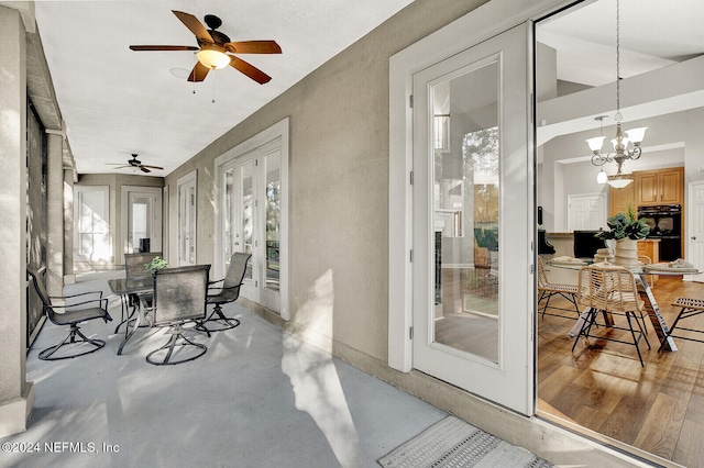 sunroom featuring ceiling fan with notable chandelier