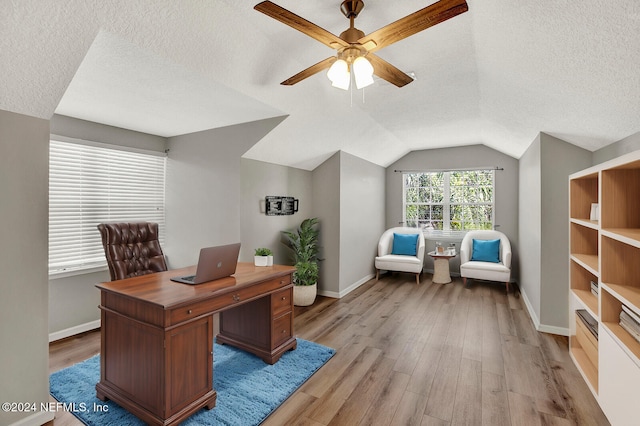 office area featuring light hardwood / wood-style flooring, a textured ceiling, lofted ceiling, and ceiling fan