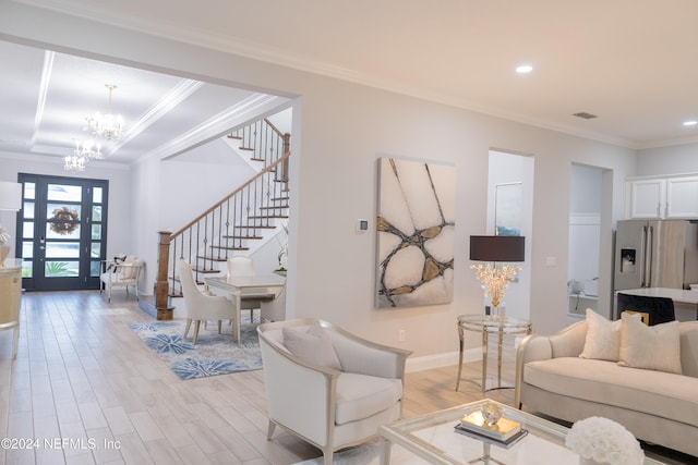 living room featuring light hardwood / wood-style floors, an inviting chandelier, ornamental molding, and french doors