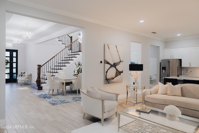 living room with a chandelier, french doors, crown molding, and light hardwood / wood-style floors