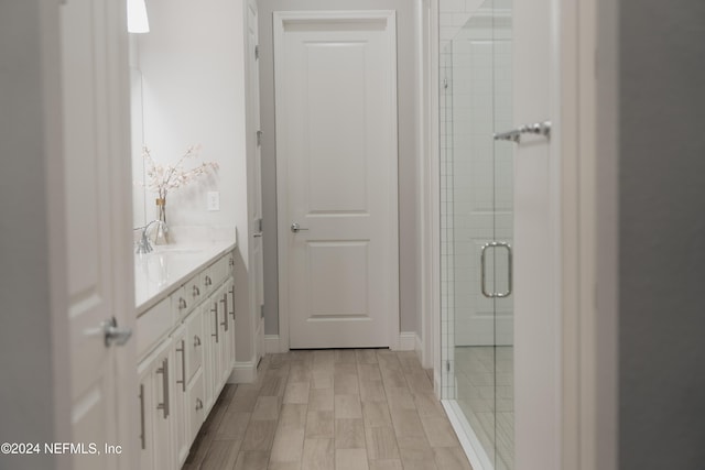 bathroom featuring vanity, hardwood / wood-style flooring, and a shower with shower door