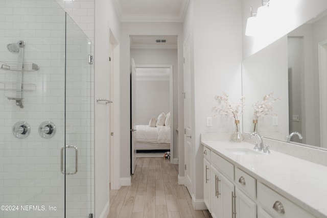 bathroom with vanity, an enclosed shower, hardwood / wood-style floors, and ornamental molding