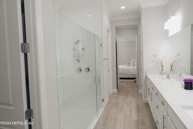 bathroom with vanity, hardwood / wood-style flooring, ornamental molding, and a shower with shower door