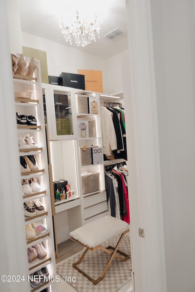 spacious closet with a notable chandelier and hardwood / wood-style flooring