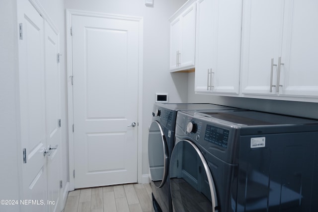 laundry room featuring light hardwood / wood-style flooring, cabinets, and separate washer and dryer