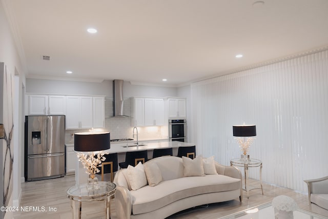 living room featuring light hardwood / wood-style floors, ornamental molding, and sink