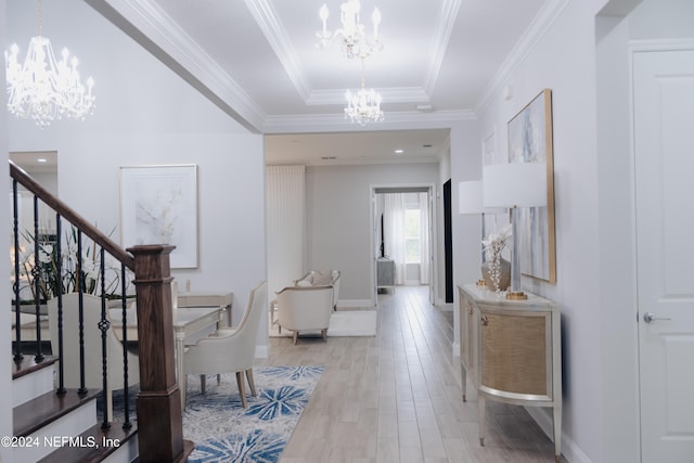 hallway featuring light wood-type flooring, a raised ceiling, ornamental molding, and a chandelier