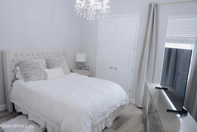 bedroom featuring a closet, a chandelier, and light wood-type flooring