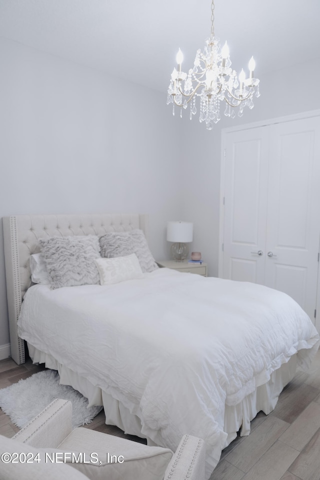 bedroom featuring a chandelier, light hardwood / wood-style flooring, and a closet