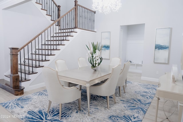 dining space featuring a notable chandelier, hardwood / wood-style flooring, and a towering ceiling