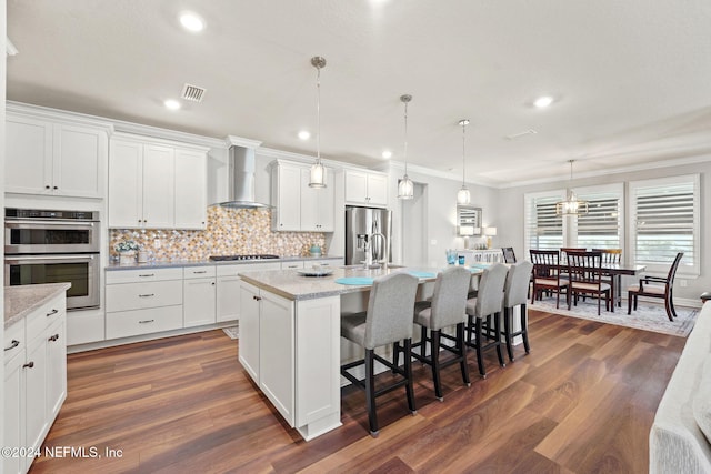 kitchen with wall chimney range hood, white cabinets, visible vents, stainless steel appliances, and dark wood-style flooring