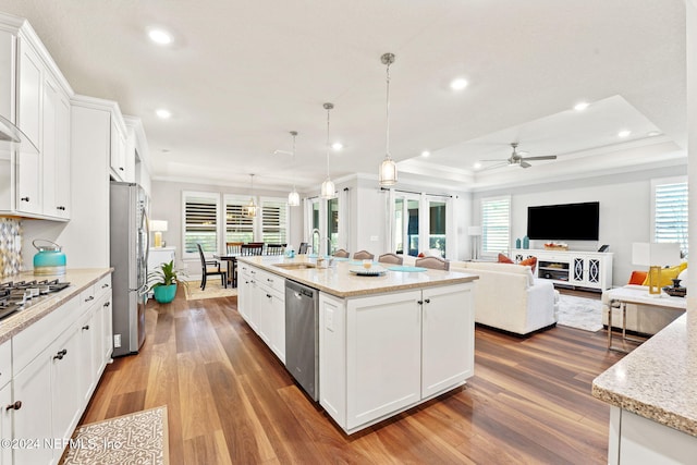 kitchen with sink, an island with sink, white cabinetry, stainless steel appliances, and decorative light fixtures