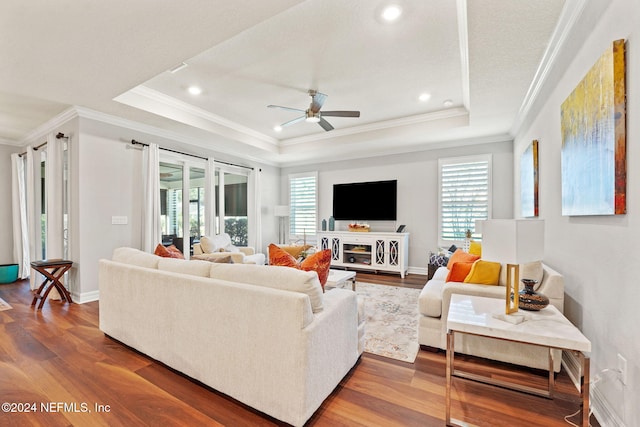 living room with crown molding, a ceiling fan, wood finished floors, and a raised ceiling