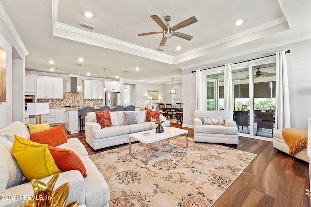 living room with ornamental molding, hardwood / wood-style floors, a raised ceiling, and ceiling fan