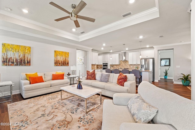 living room with dark wood-type flooring, baseboards, visible vents, a ceiling fan, and crown molding