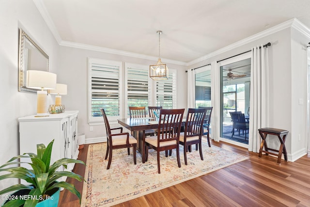 dining space featuring wood finished floors, crown molding, and baseboards