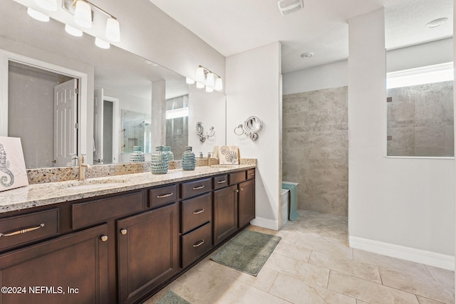 bathroom with vanity, tiled shower, and plenty of natural light