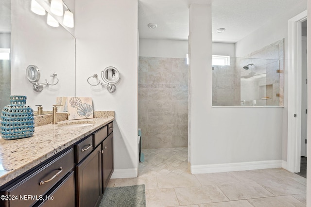 bathroom with vanity, a tile shower, and tile patterned flooring